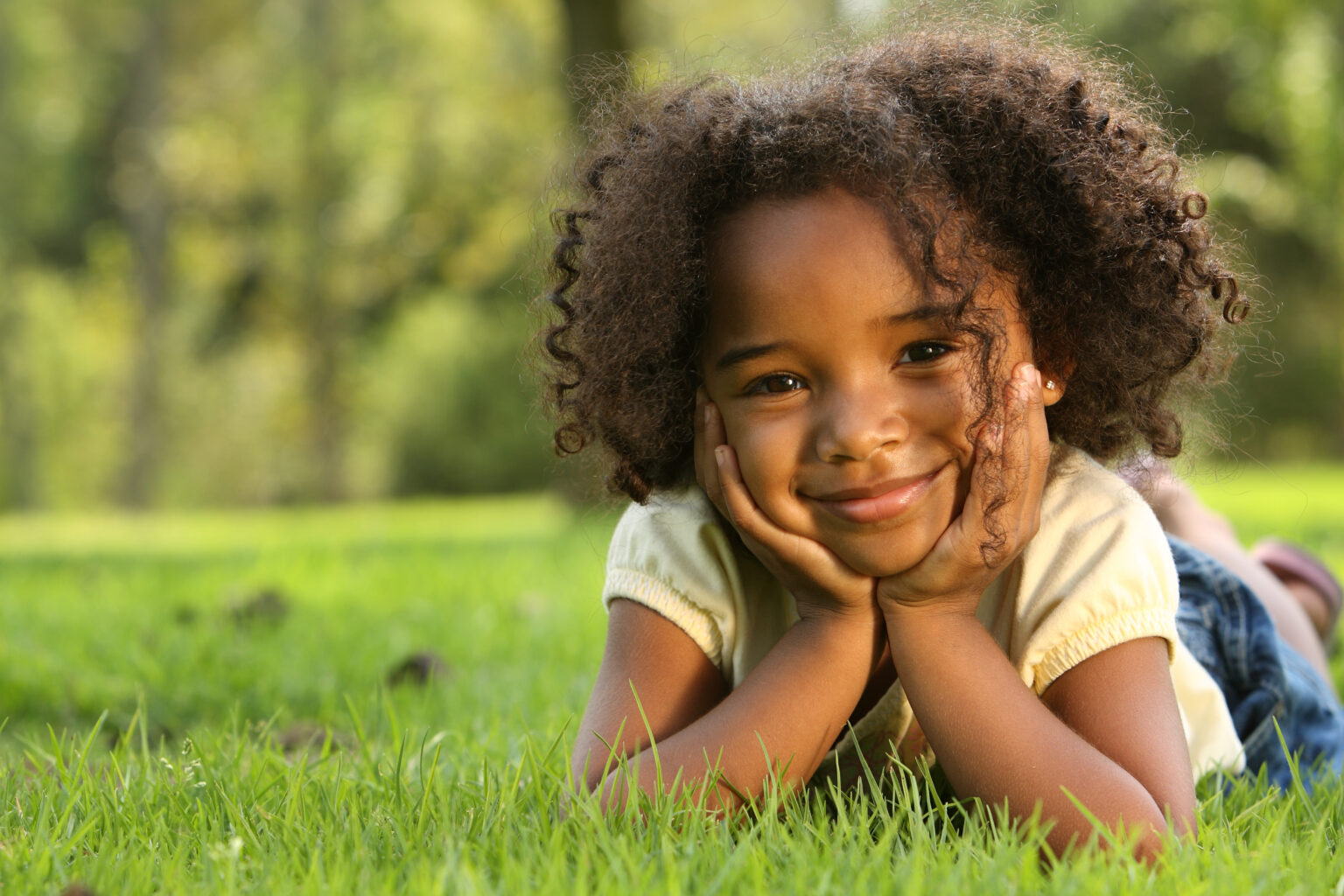 Smiling child lying in the grass.