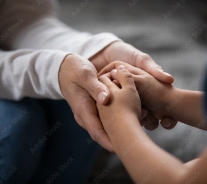 An adult holding a child's hands