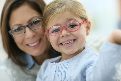 Mother and daughter with glasses smiling at the camera