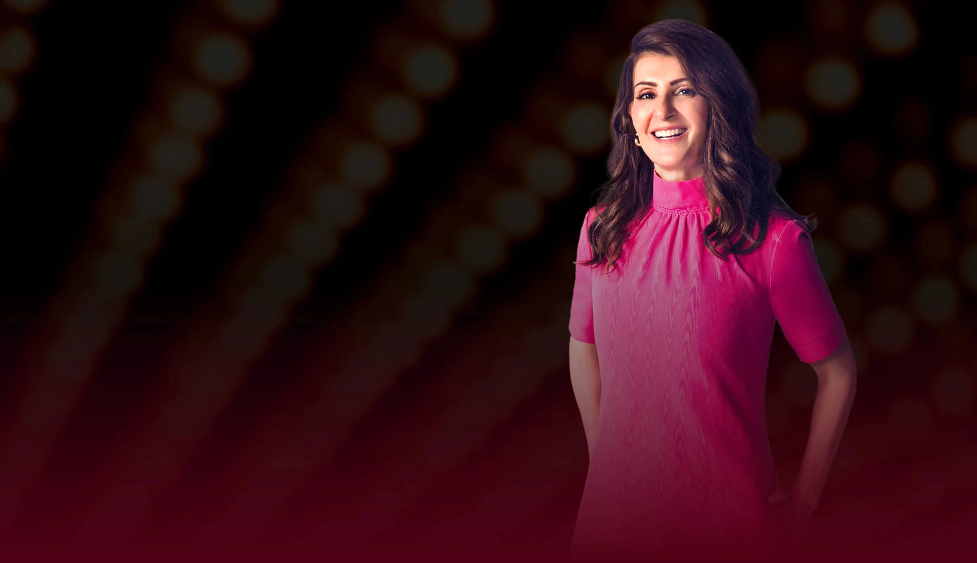 Nia Vardalos smiling in a pink dress against a blurred background of lights, promoting the fundraising event for the Center for the Rights of Abused Children.