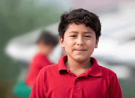 Smiling boy in a red shirt, representing foster children benefiting from Arizona Governor Hobbs' new law on social security and survivor benefits.
