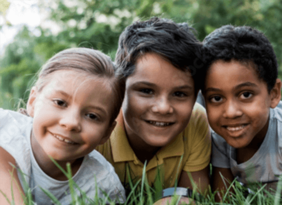 Three children smiling together in grass, representing child welfare and safety in Arizona's legislative reforms.