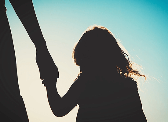 Silhouette of a parent holding a child's hand, symbolizing child protection and family support in the context of child welfare advocacy.