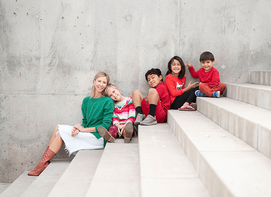 Darcy Olsen with children sitting on stairs, smiling and promoting family togetherness and support for child welfare.