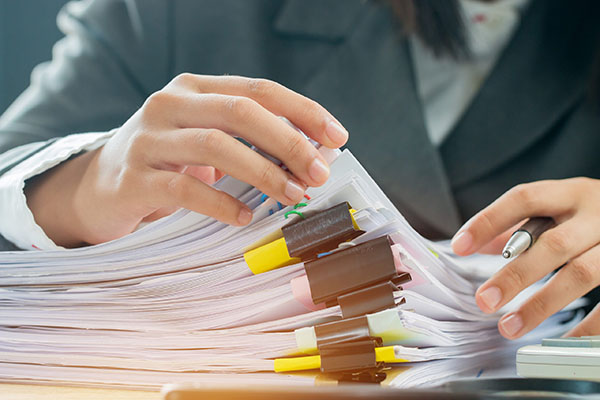 Person organizing a stack of documents with binder clips, symbolizing the review of child abuse cases and advocacy for children's rights.